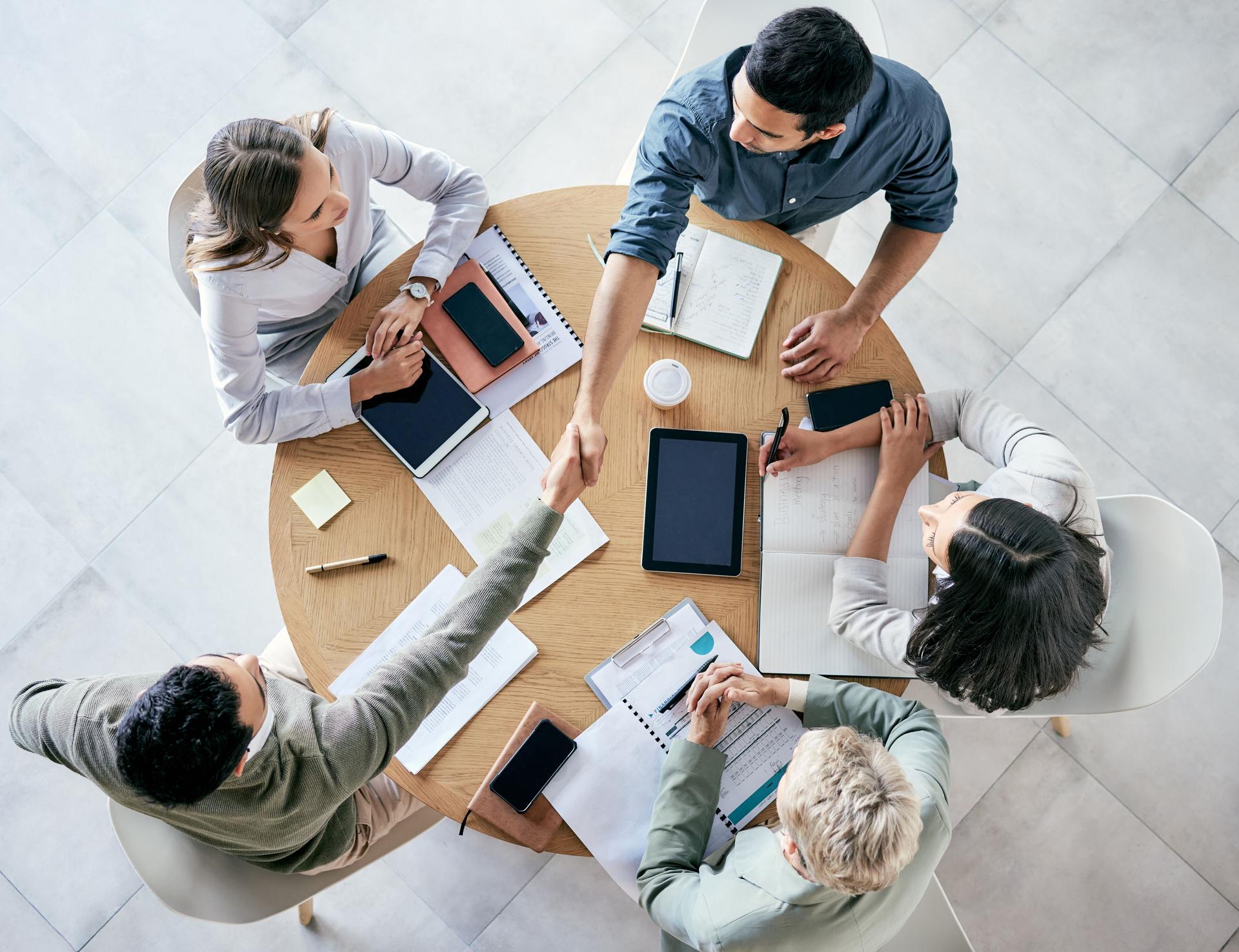 Shot of  businessmen shaking hands during a team meeting in a modern office